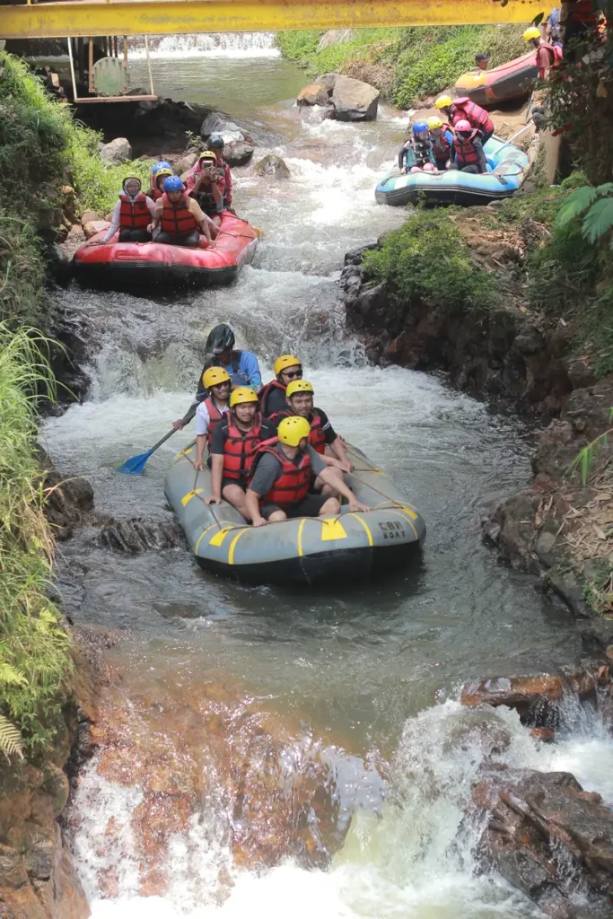 Rombongan Mr Otewe Tour & Travel memasuki Jeram Start Sungai Palayangan; guide FAST Rafting mengendalikan perahu dari belakang sementara peserta duduk berpegangan pada tali perahu sambil tersenyum lebar menyambut jeram pertama.
