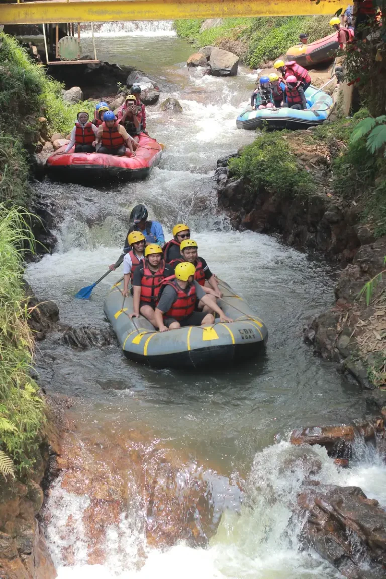 Rombongan Mr Otewe Tour & Travel memasuki Jeram Start Sungai Palayangan; guide FAST Rafting mengendalikan perahu dari belakang sementara peserta duduk berpegangan pada tali perahu sambil tersenyum lebar menyambut jeram pertama.